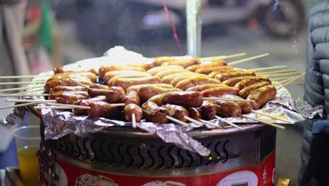 sausages cooking on skewers over a grill