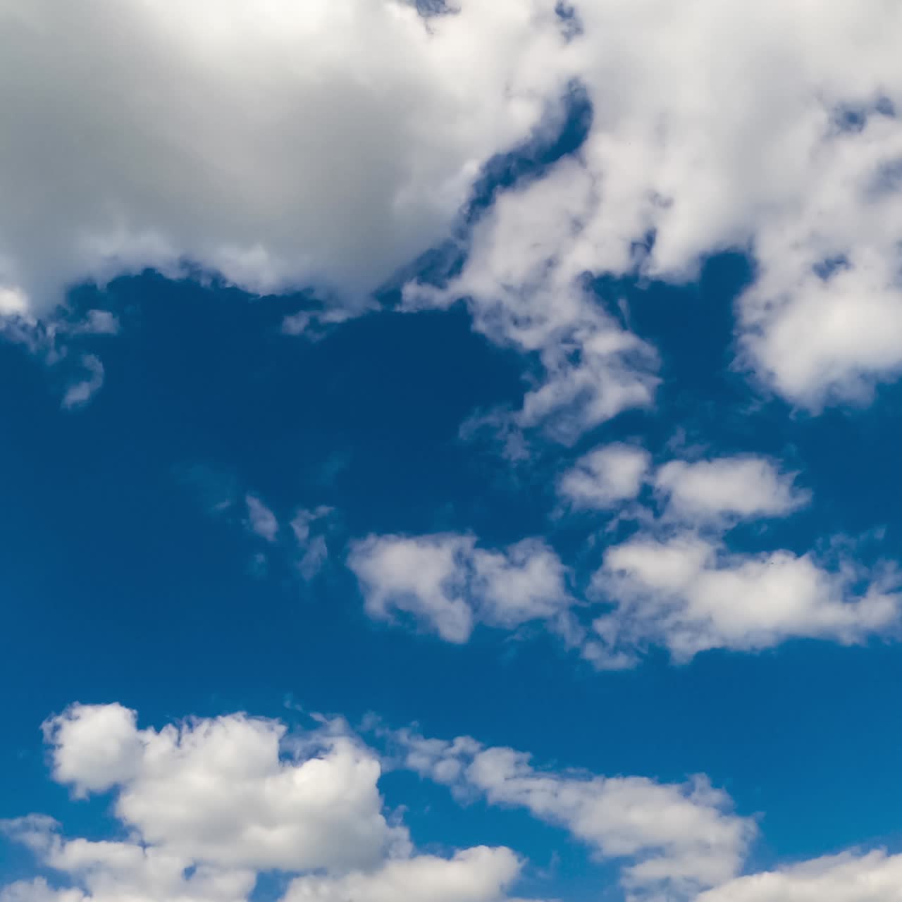 Cloudscape in the azure sky. Big cloud dissolving into little white clouds. Low angle view. Timelapse