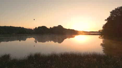 sunrise over a calm lake with a hot air balloon