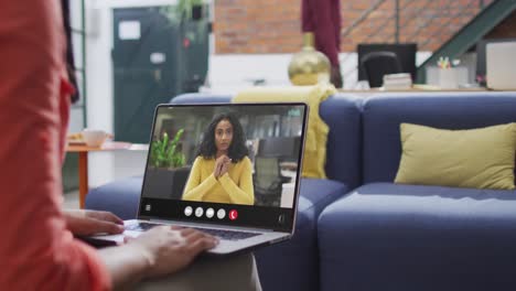 Mujer-Birracial-Usando-Una-Computadora-Portátil-Para-Videollamada,-Con-Un-Colega-De-Negocios-En-La-Pantalla