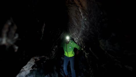 male hiker exploring a dark cave 4k