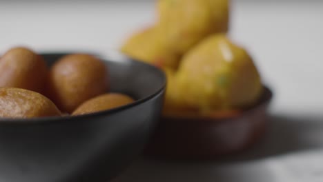 close up of gulab jamun and laddoo in bowls celebrating muslim festival of eid