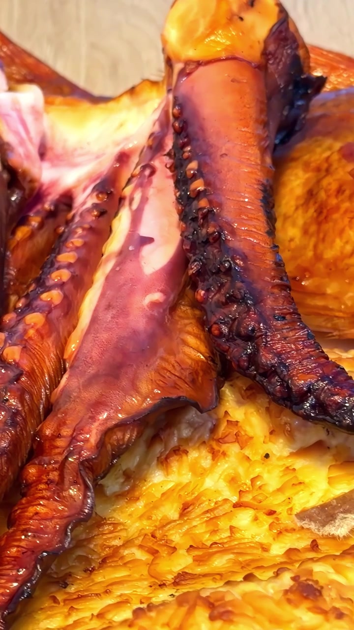 Teneri tentacoli di polpo grigliati adagiati su una crosta di pizza al formaggio dorata e croccante, che evidenziano ricche consistenze e sapori intensi. Video verticale, ideale per i social media.