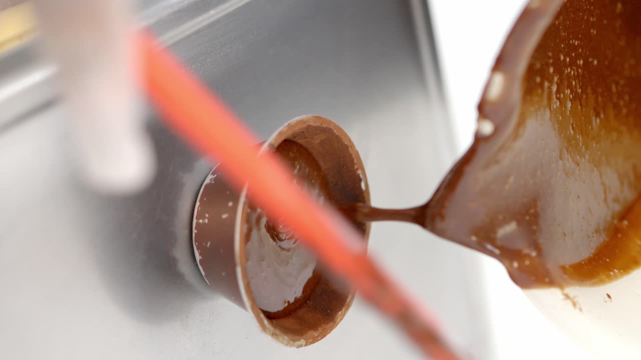 식품 공장의 플라스틱 냄비에 바삭하게 코팅된 핫초콜릿 제공