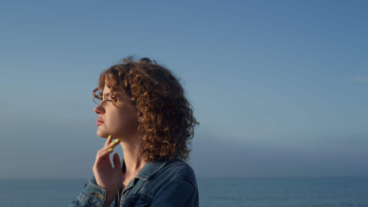 Sad woman standing on sea beach. Portrait of upset girl holding hand on face