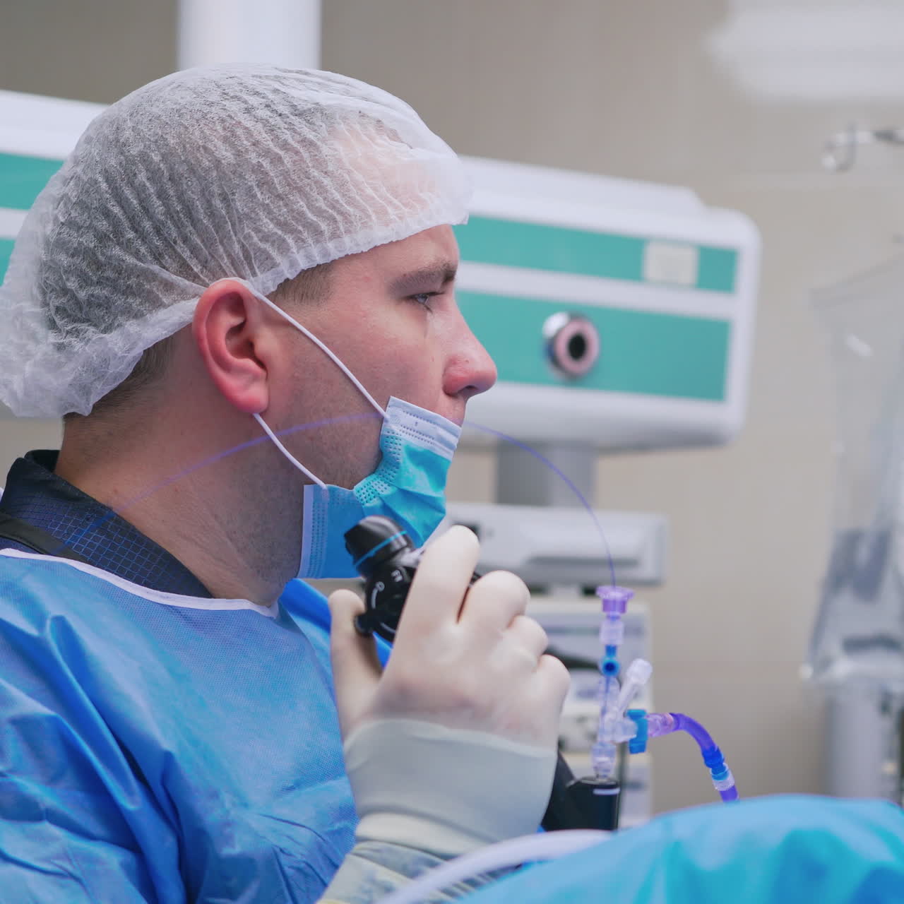 Doctor in medical uniform doing endoscopy. Side view of a surgeon working with new medical equipment in operating room. New technologies in medicine.