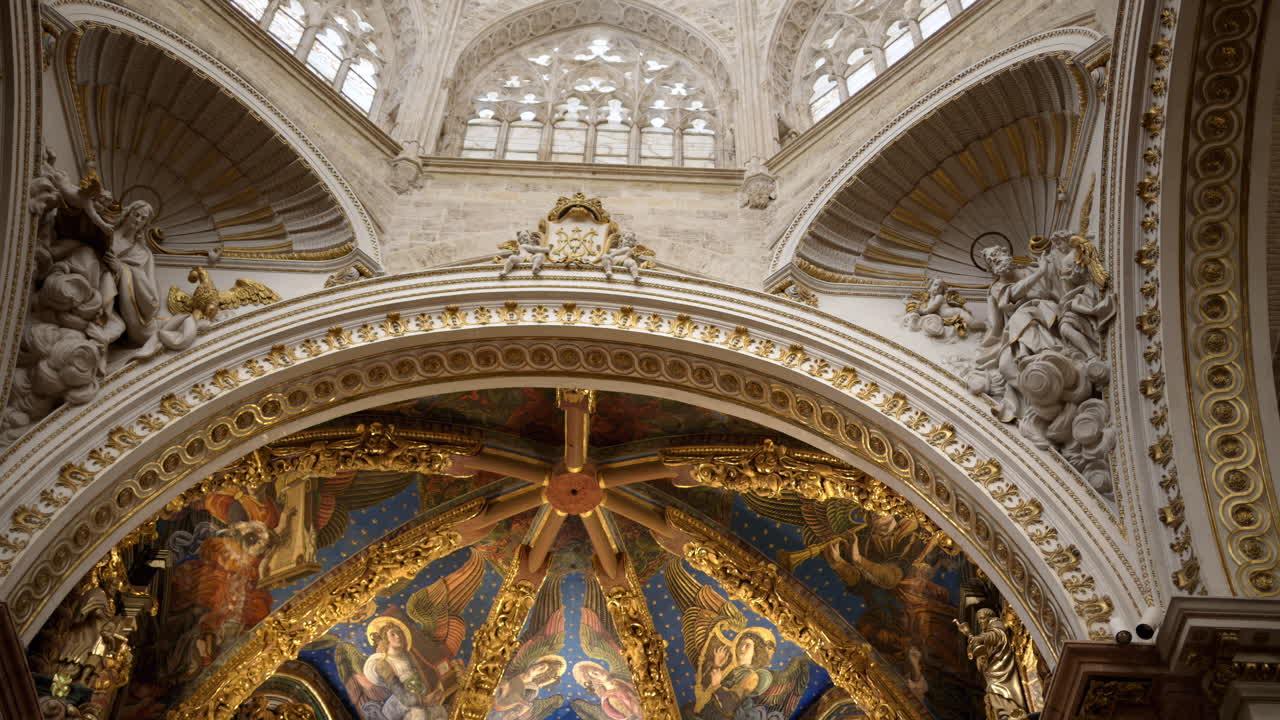 Valencia, Spain - May 28, 2025: Upward view of an ornate chapel dome with blue, star-studded paintings and gilded ribs, framed by heavily sculpted white and gold archwork