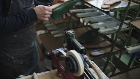 artesano pulsa la suela de una sandalia en la maquinaria en el taller