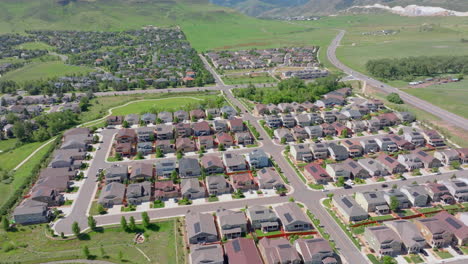 Vista-Aérea-Cinematográfica-Lenta-De-Un-Barrio-Suburbano-En-Verano-Con-Paneles-Solares-Renovables-Y-Verdes-En-La-Azotea-Para-Ayudar-Al-Clima