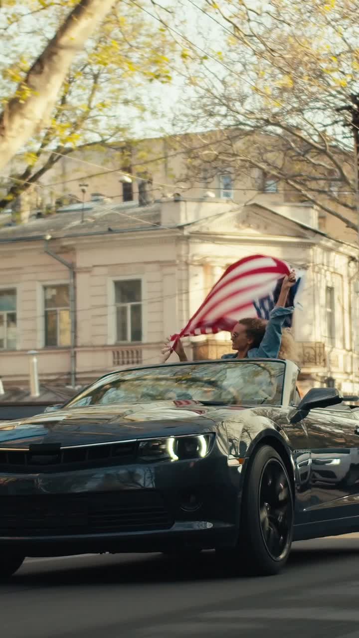 Woman waving American flag in a convertible car
