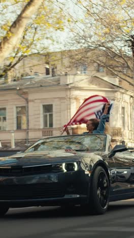 woman waving american flag in a convertible car