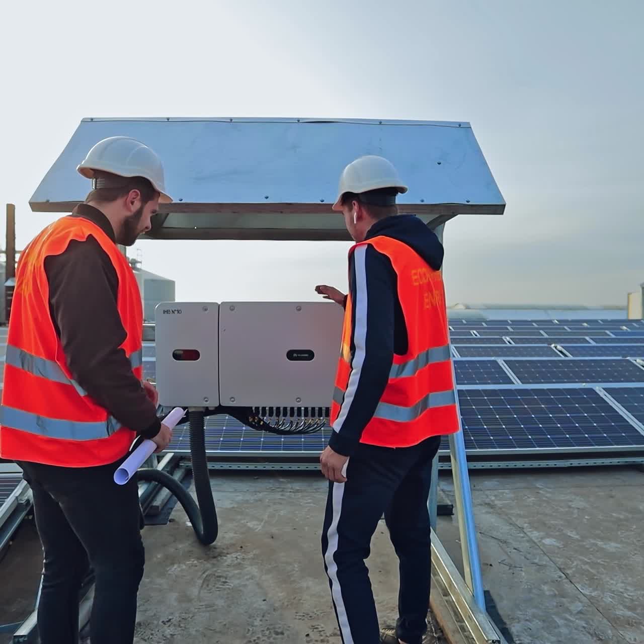 Solar panels for a renewable energy. Workers in protective orange uniform talking on the big power station with solar panels.