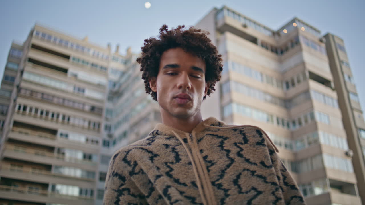 Hispanic man standing casually in city environment at windy weekend closeup