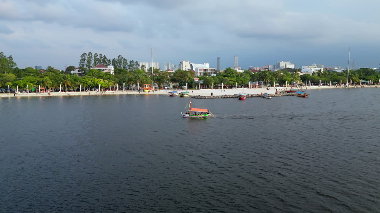 un pequeño barco recorre la orilla de la playa de ancol al atardecer en jakarta, indonesia.