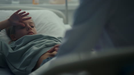 doctor touching patient stomach in emergency ward closeup. sick kid lying in bed