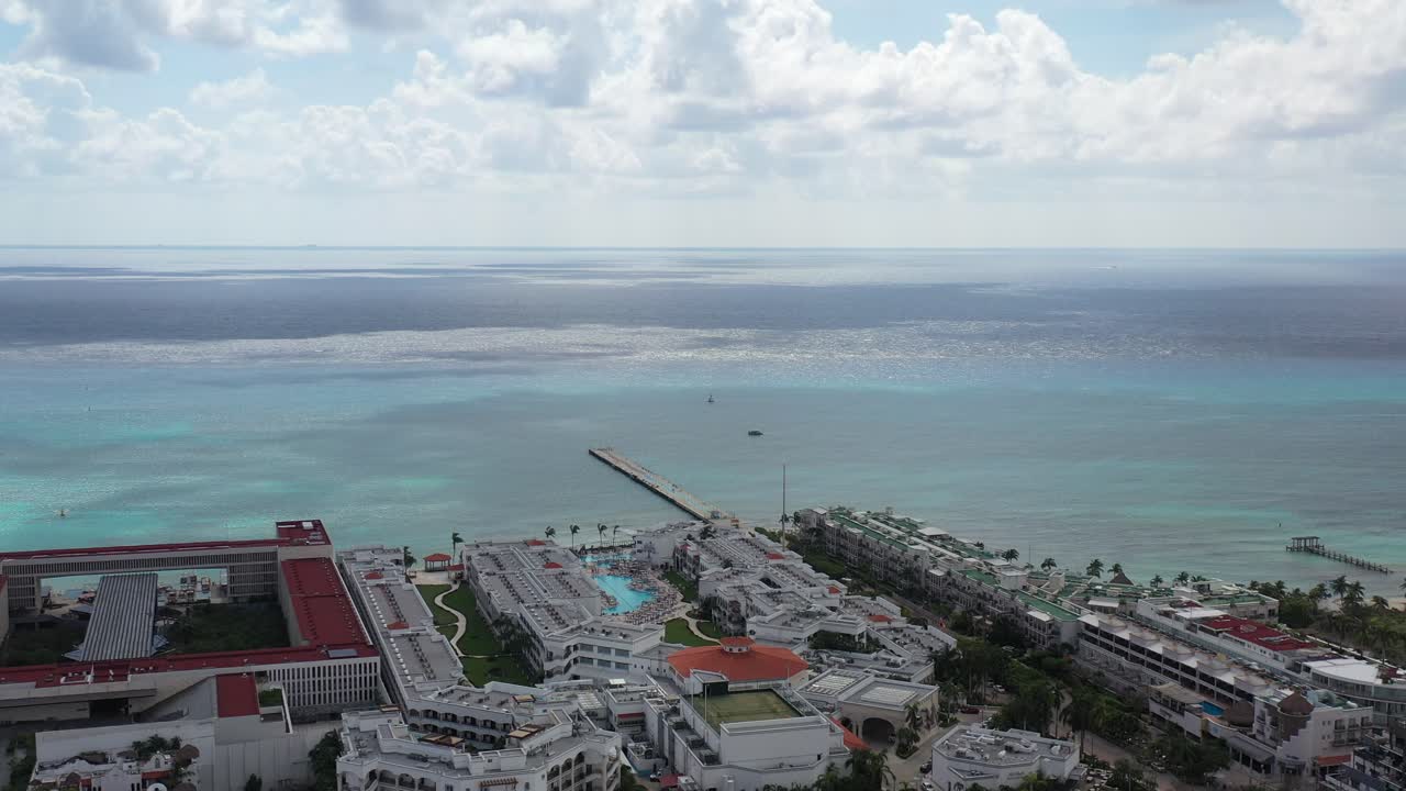 바다로 향하는 항공 샷은 캐리비안과 부두 옆에 있는 큰 호텔을 보여줍니다.