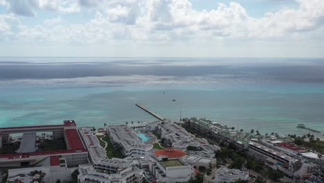 toma aérea que se dirige al mar muestra un gran hotel junto al caribe y un muelle