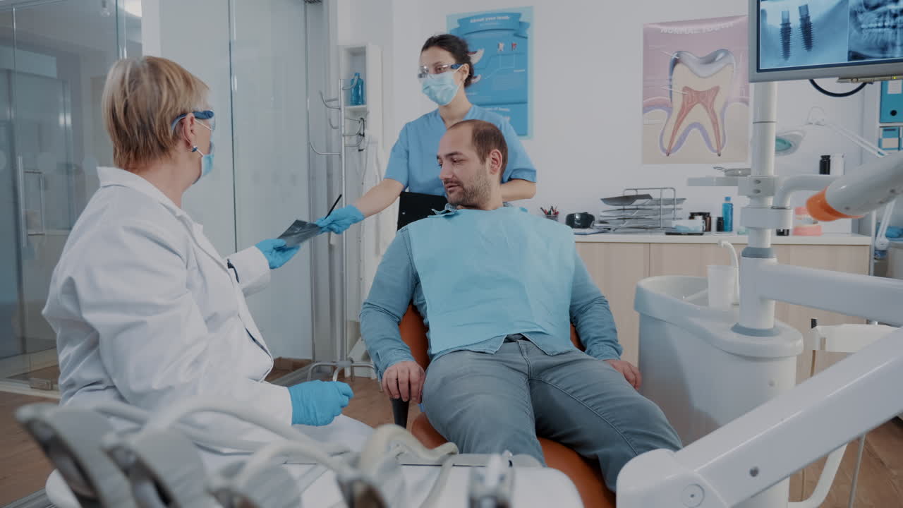 estomatólogo mostrando los resultados de las radiografías de la prótesis al paciente en la visita de chequeo