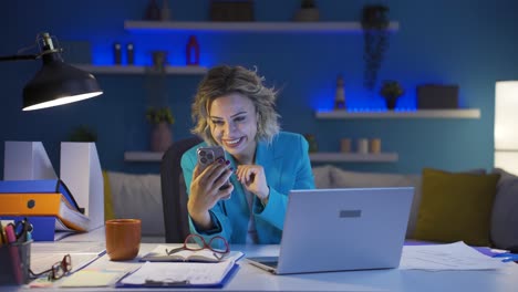 una donna che lavora in ufficio a casa che parla al telefono facetime felicemente.