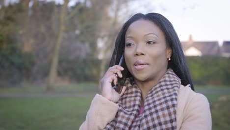 confident black woman talking phone in park