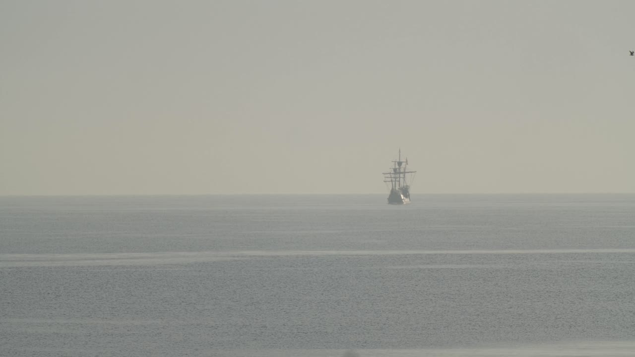 페르디난드 마젤란 나오 빅토리아 카락 보트 복제품은 일출 시 지중해에서 멀리 항해하며 새는 60fps의 느린 동작으로 잔잔한 바다에서 날아갑니다.