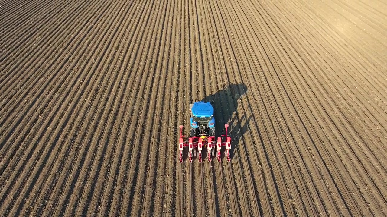 Aerial View of Tractor Planting Seeds in Large Agricultural Field