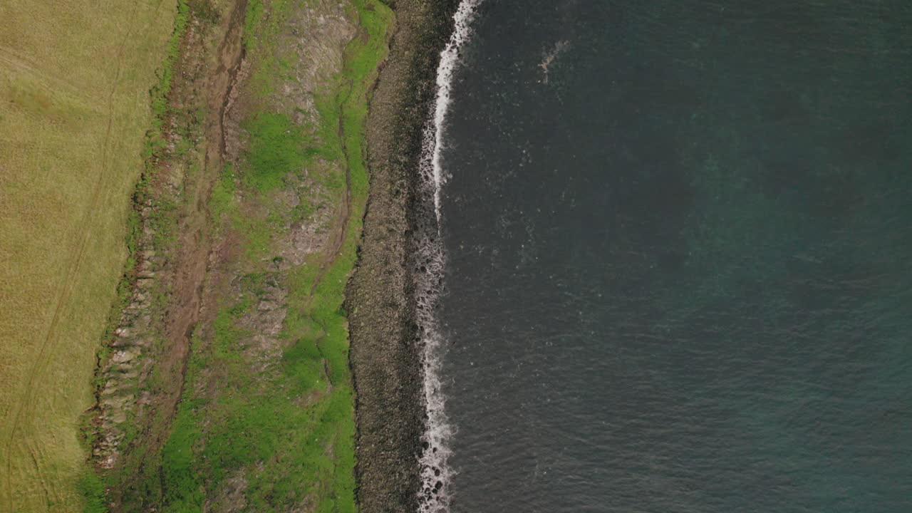 paso elevado a vista de pájaro sobre la costa rocosa y los acantilados verdes de la isla grimsey, islandia
