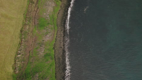 Paso-Elevado-A-Vista-De-Pájaro-Sobre-La-Costa-Rocosa-Y-Los-Acantilados-Verdes-De-La-Isla-Grimsey,-Islandia