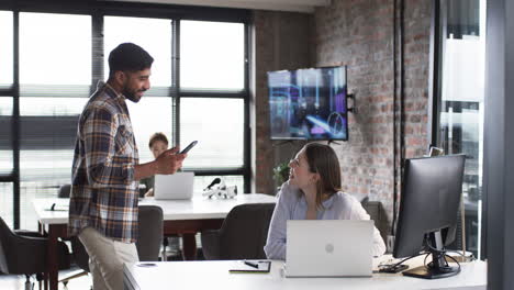 young caucasian woman discusses business with a bearded colleague at a modern office
