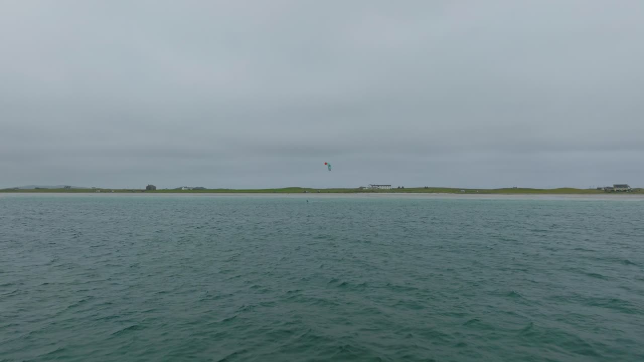 toma aérea de un solo kitesurfista que cabalga hacia el avión no tripulado en la isla de tiree, escocia