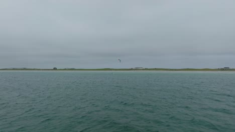 toma aérea de un solo kitesurfista que cabalga hacia el avión no tripulado en la isla de tiree, escocia
