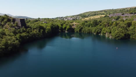 Aerial-view-Dorothea-slate-mining-quarry-woodland-in-Snowdonia-valley-with-gorgeous-Welsh-blue-lake