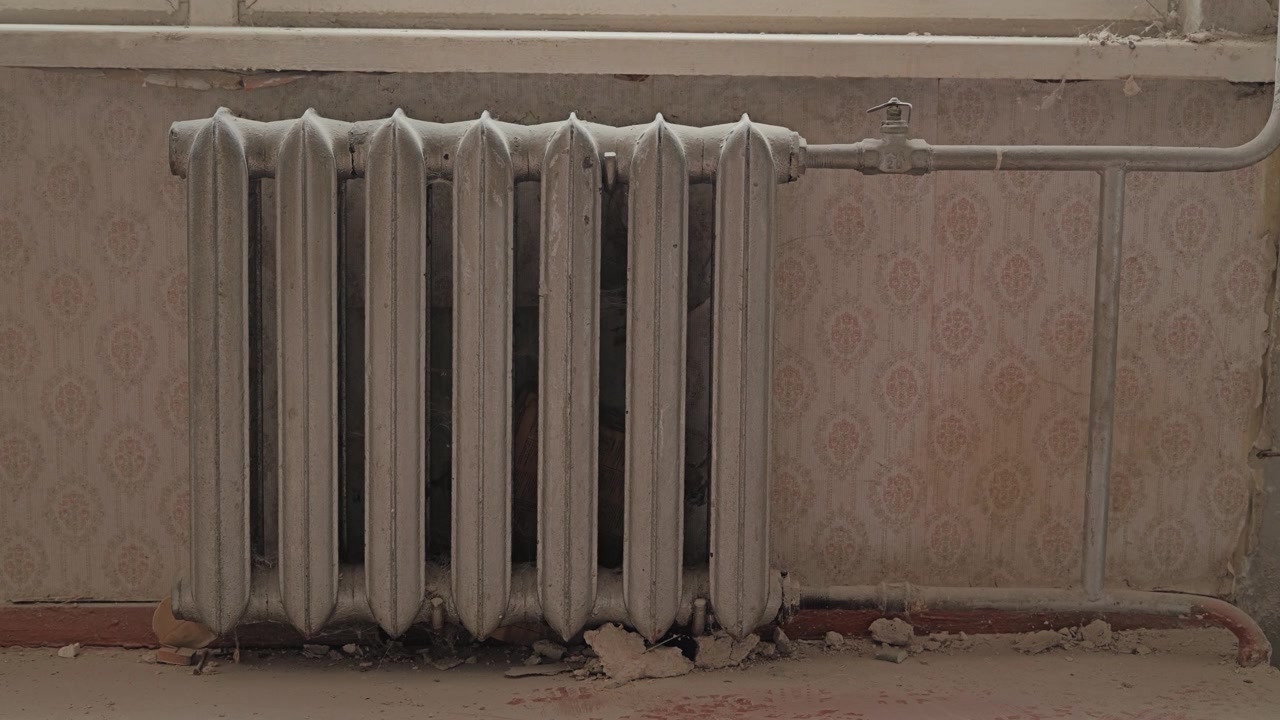 Warm sunlight falls across a vintage heating radiator in old apartment interior