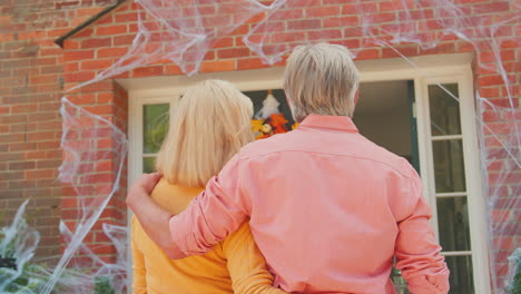 grandparents at home putting up halloween decorations for trick or treat