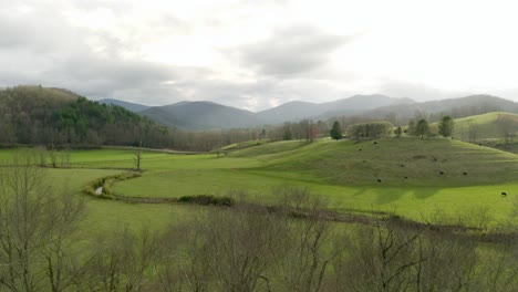 green pastures, rolling hills wandering river and distant mountains make up the landscape in this aerial view of the appalachian mountains