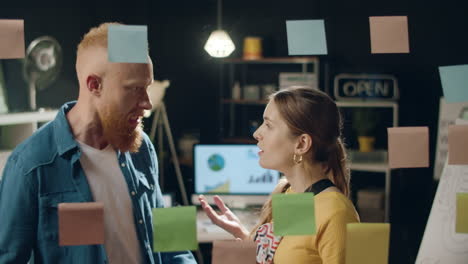 business man conflicting with female partner over stickers at hipster office.