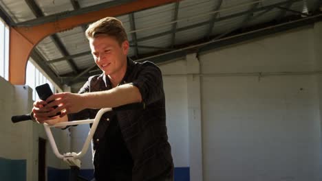 BMX-rider-using-smartphone-in-an-empty-warehouse