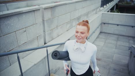 woman walking up stairs with yoga mat and water bottle