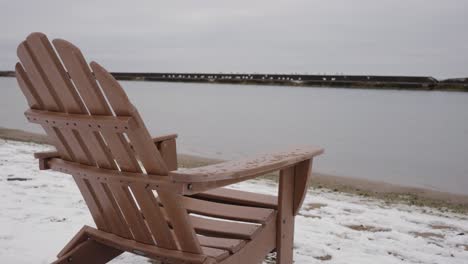 silla reclinable de plástico con vistas al lago ontario durante un día de invierno con gaviotas blancas fuera de foco en el fondo