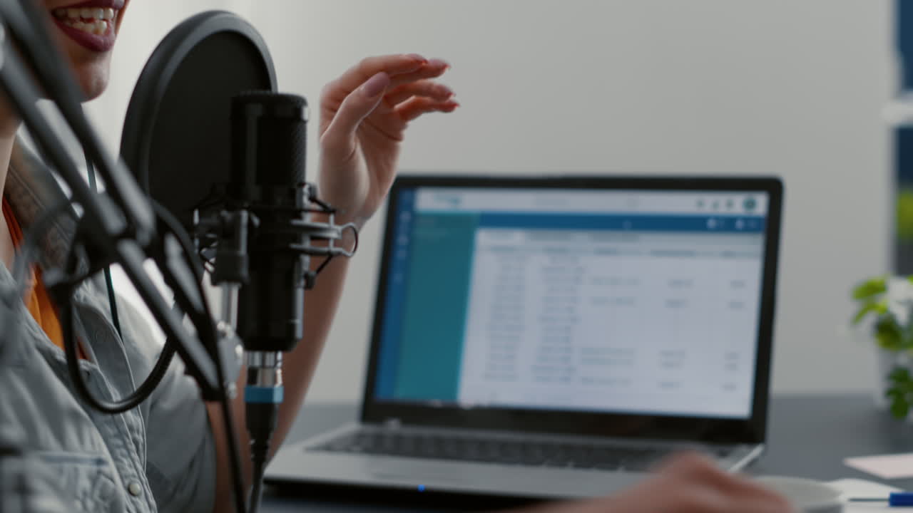 Joyful podcaster telling life stories to audience while using mixer for sound tweaking
