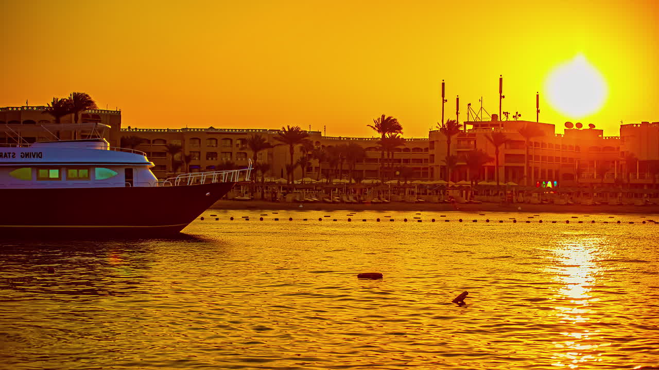 hora dorada puesta de sol junto al mar en hurghada, egipto con hotel frente al mar en segundo plano