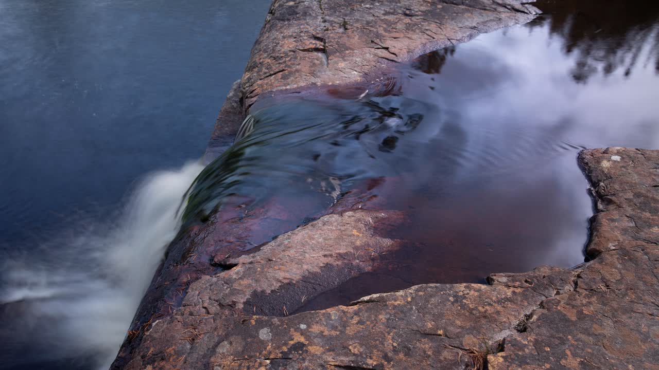 pequeña cascada y reflejo de nubes en el agua