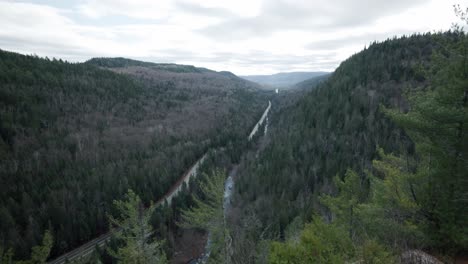 a long narrow road between forest covered mountain valley at saint-come in lanaudière region, quebec, canada