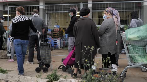 people in a grocery store queue during pandemic