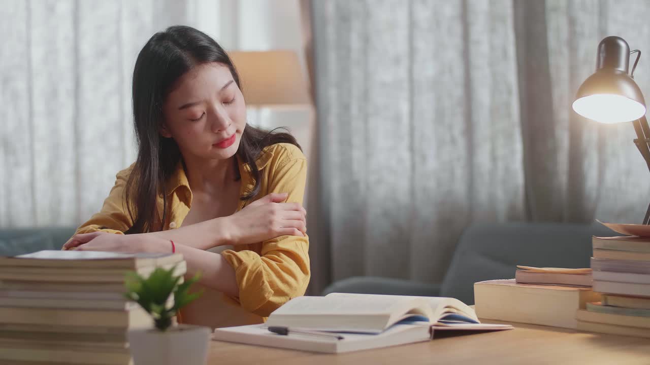 집에서 공부하는 동안 책을 읽은 후 스트레칭하는 젊은 아시아 여성