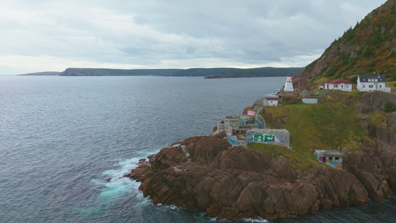 Drone footage captures Fort Amherst’s coastal village nestled on steep slopes where pastel-coloured houses cling to rocky terraces and rugged cliffs meet a calm cove
