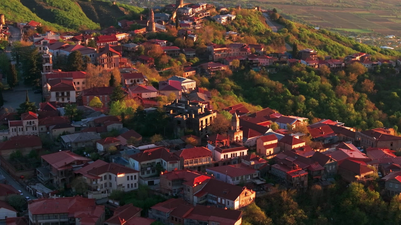 Aerial drone view of Sighnaghi, Georgia at sunrise, with golden hour light illuminating the hilltop town, scenic landscape, and charming architecture in a peaceful morning setting.