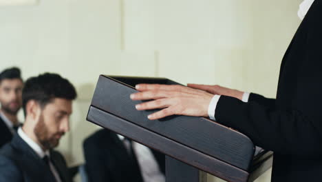 close-up view of caucasian female hands on a podium and gesticulating while businesswoman is making a speech to the audience at a conference