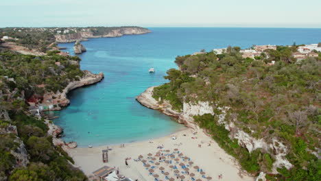 El-Agua-De-Mar-Serena-Se-Encuentra-Con-Arena-Blanca-En-Cala-Llombards-Con-Impresionantes-Acantilados-Naturales-En-Mallorca,-España