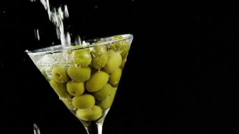 Cocktail-being-poured-into-the-glass-full-of-olives